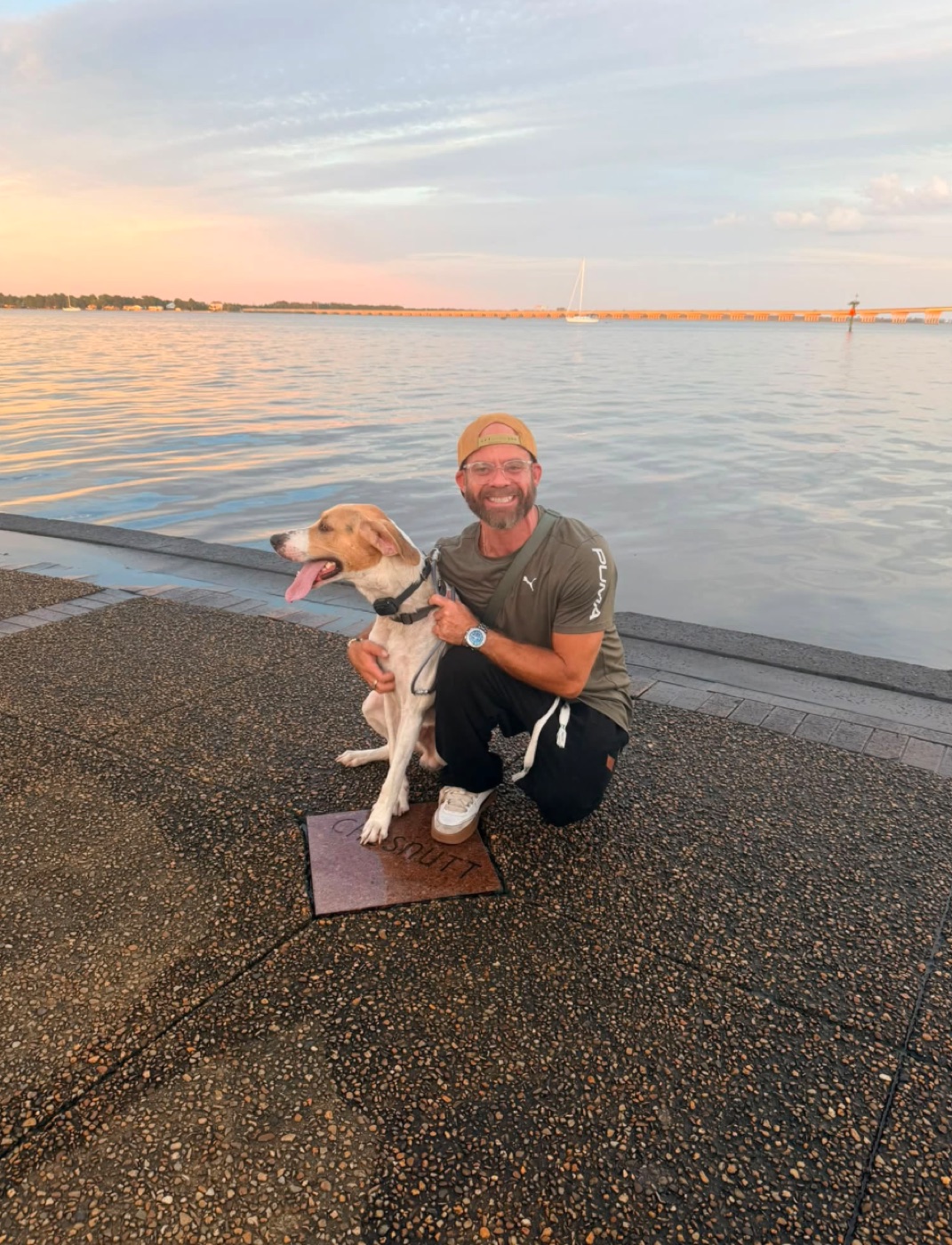 David Hahn crouched beside Reese, his hound, on the New Bern waterfront at sunset